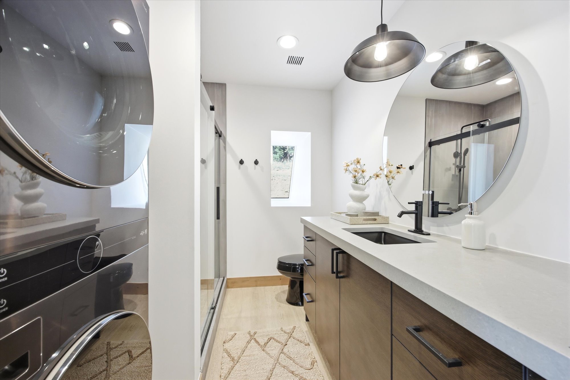 Bathroom featuring a floating wood-finish vanity with a light-toned countertop, a rectangular undermount sink, and a black wall-mounted faucet