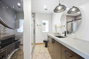 Bathroom featuring a floating wood-finish vanity with a light-toned countertop, a rectangular undermount sink, and a black wall-mounted faucet