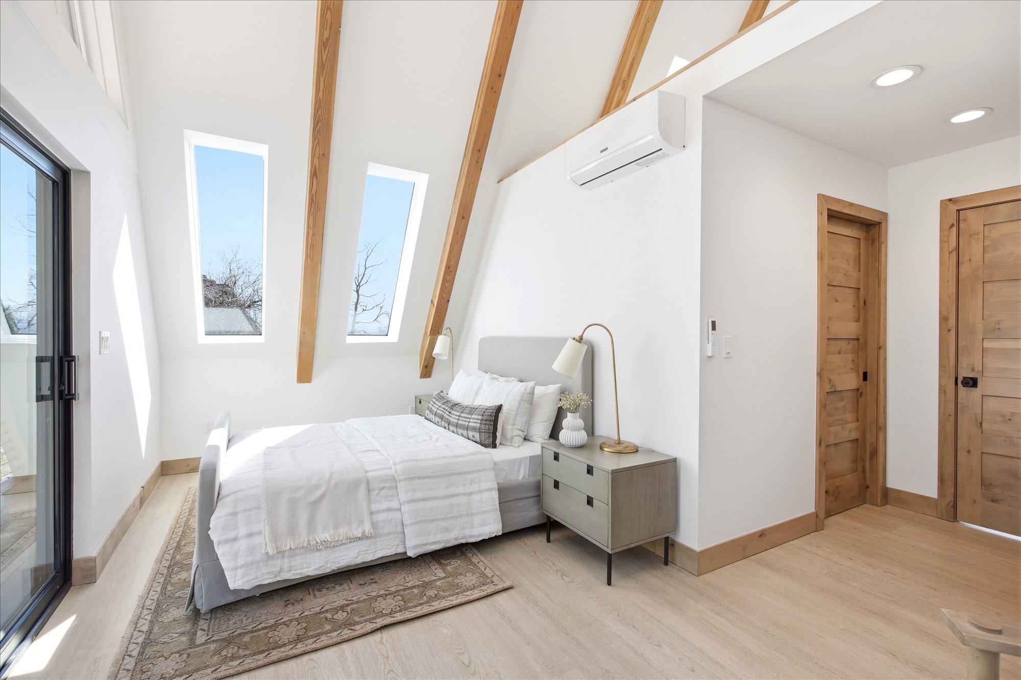 Bright room with vaulted ceiling featuring exposed wood beams and light wood-finish flooring