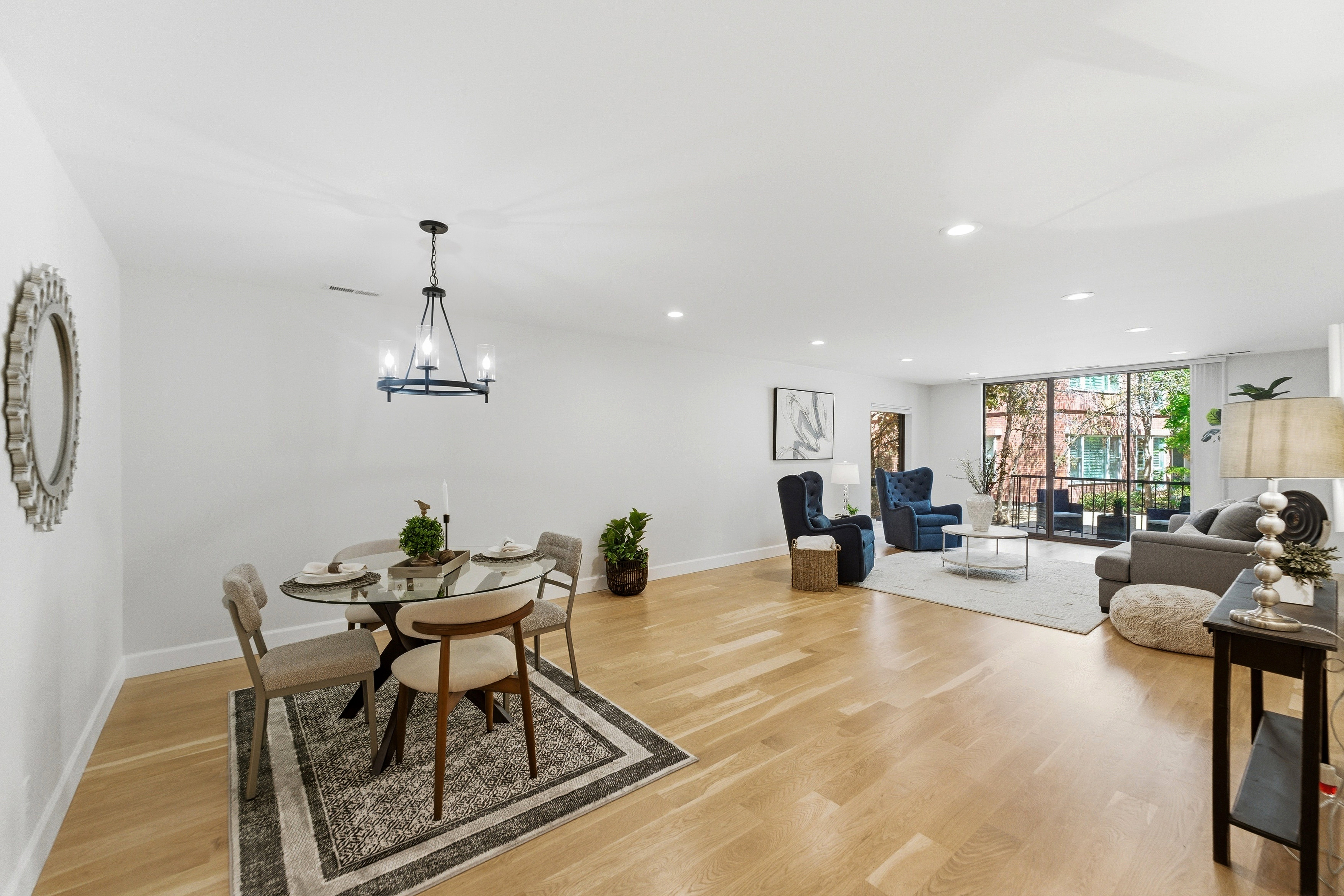Open-concept living space featuring hardwood flooring, recessed lighting, a modern chandelier, and a large window wall