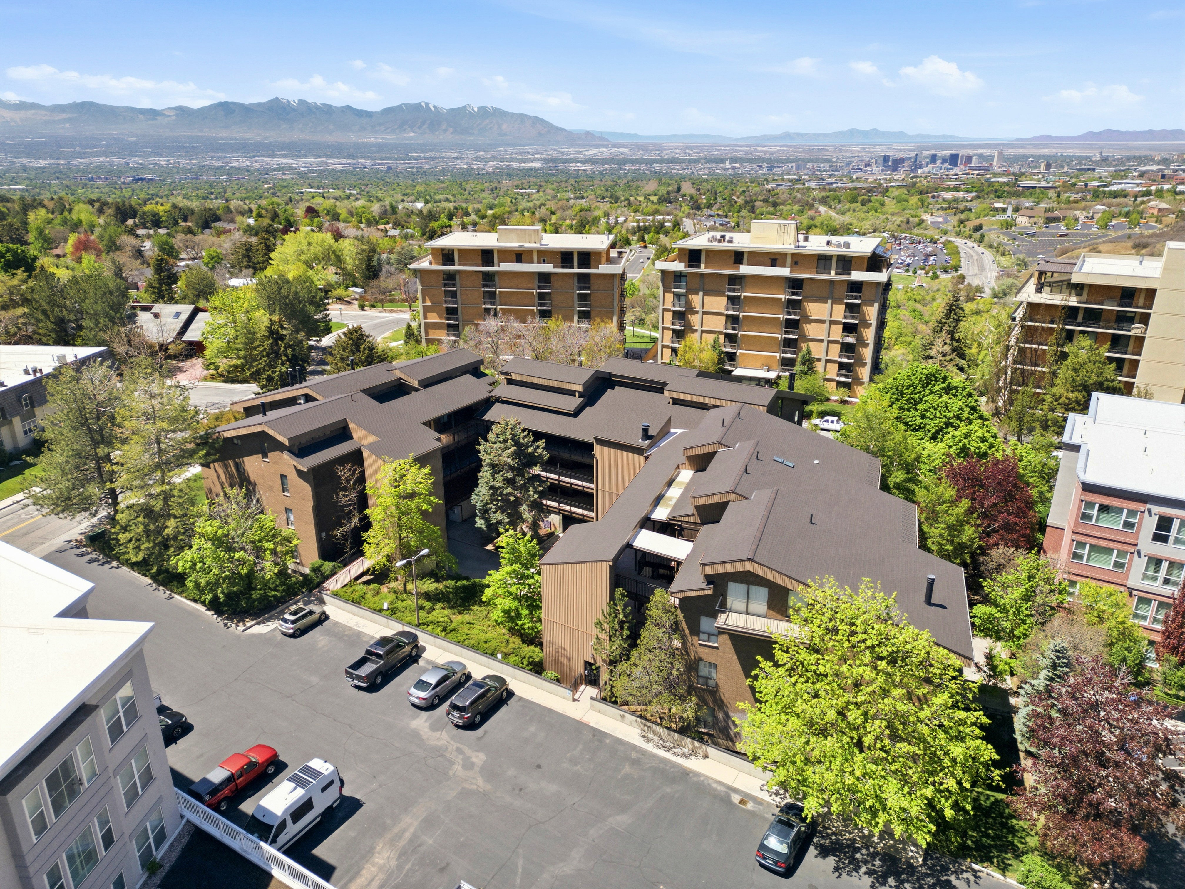 Multi-story residential complex featuring brown-toned exterior, dark sloped roofs, and private balconies