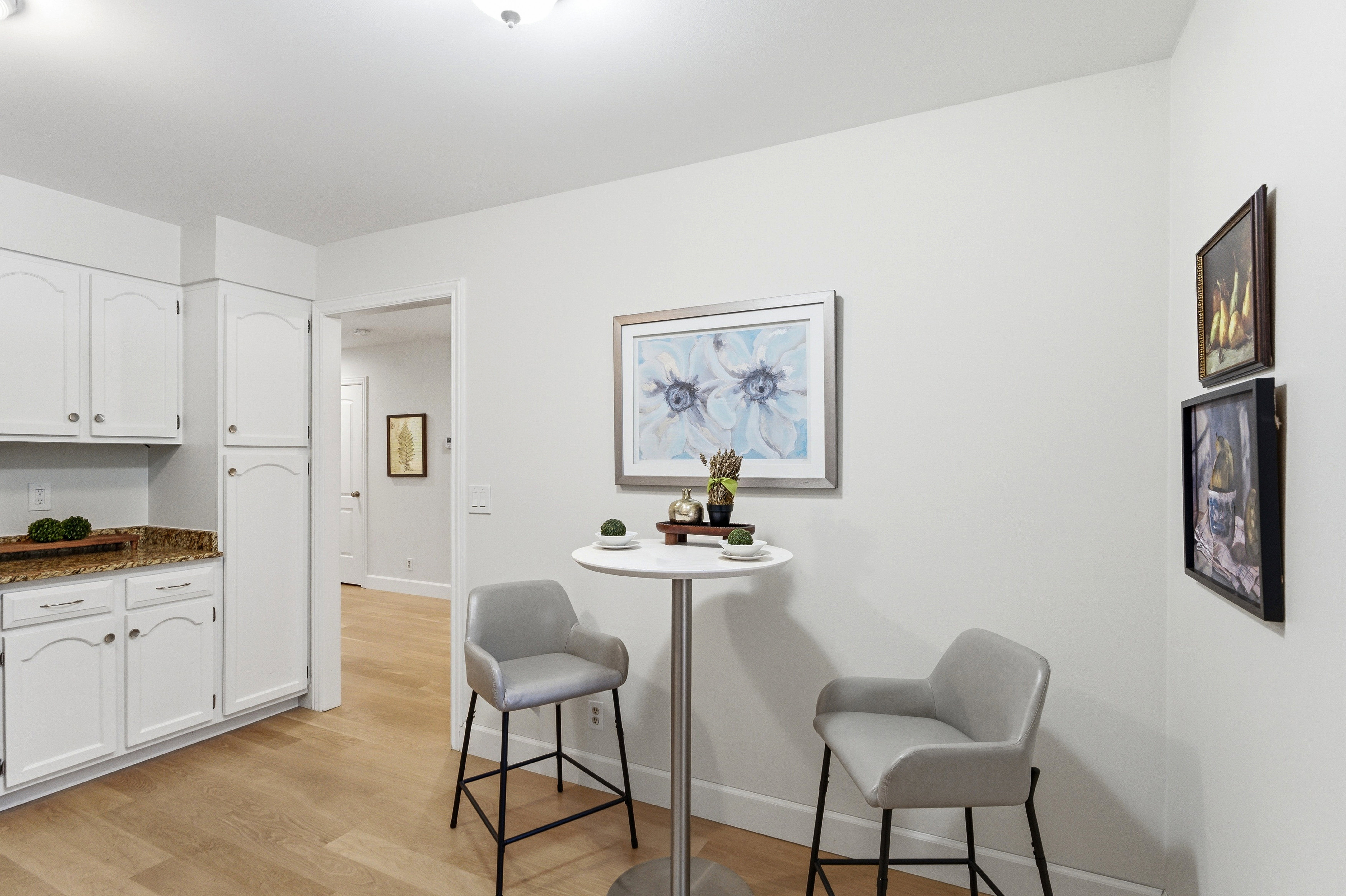 Kitchenette area featuring white cabinetry, granite countertops, and wood-finish flooring