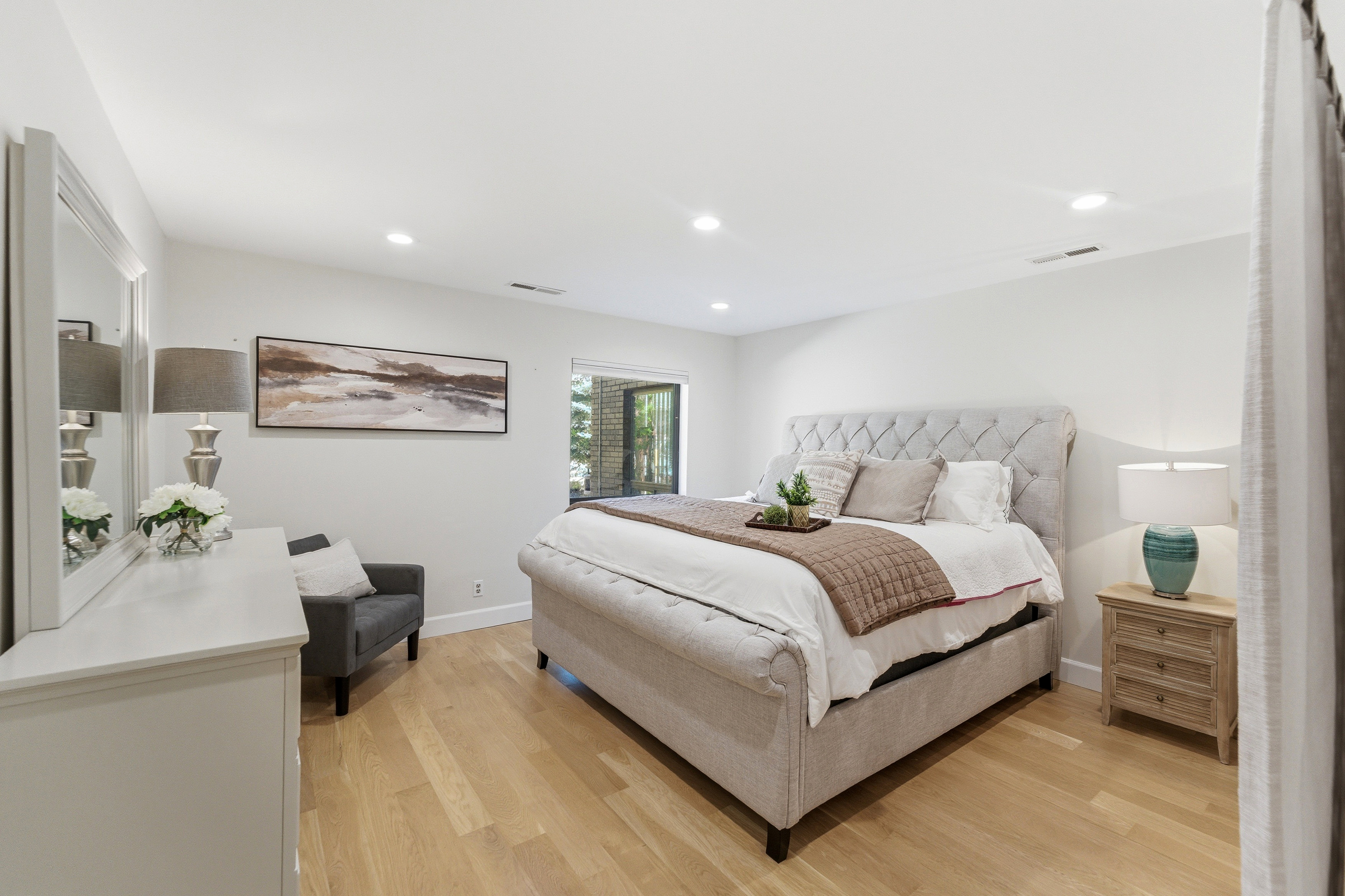Spacious bedroom featuring light wood-finish flooring, recessed lighting, and a large window offering exterior views