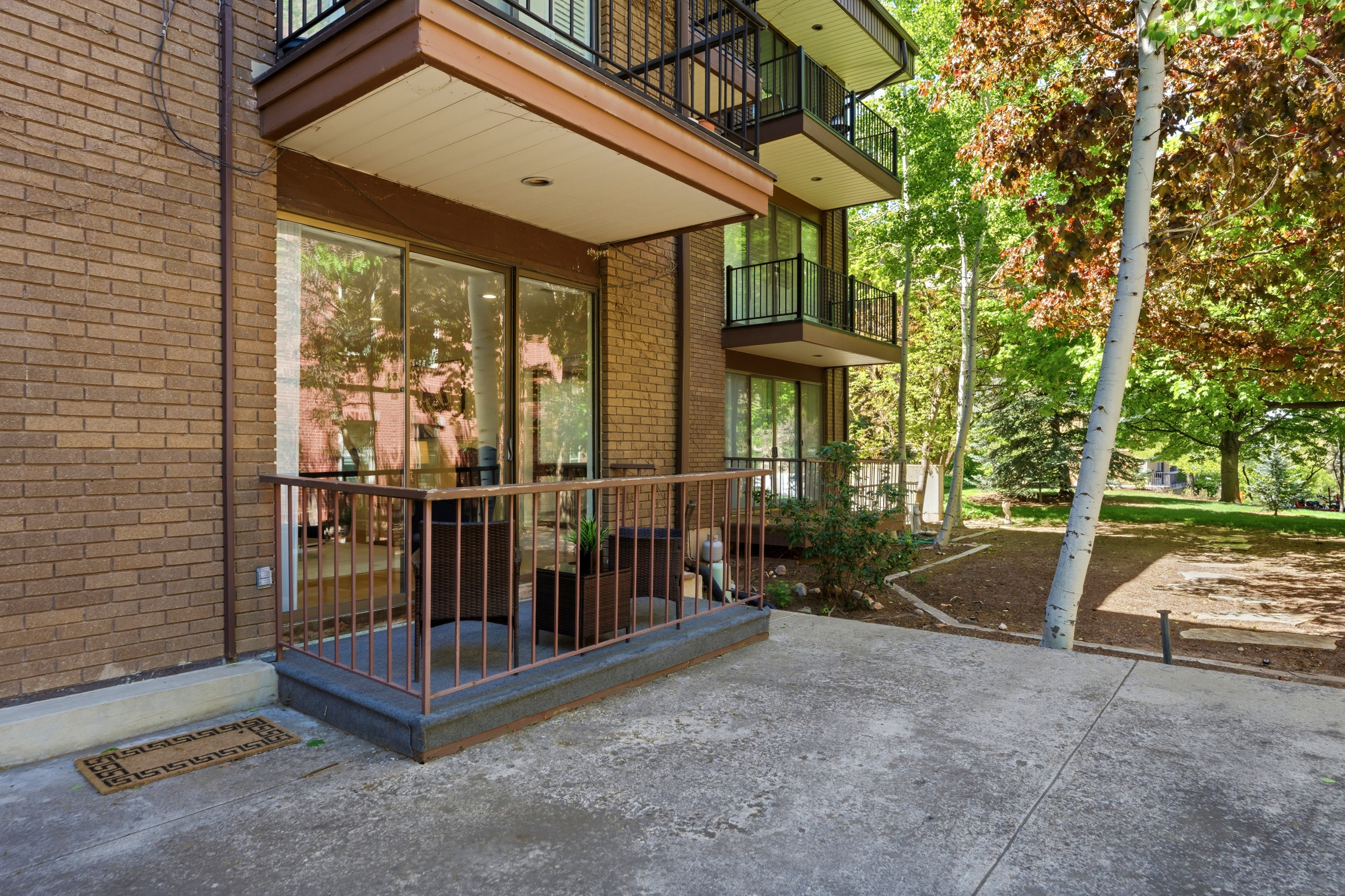 Brick exterior featuring a private patio with metal railing, sliding glass door access, and a concrete paver area