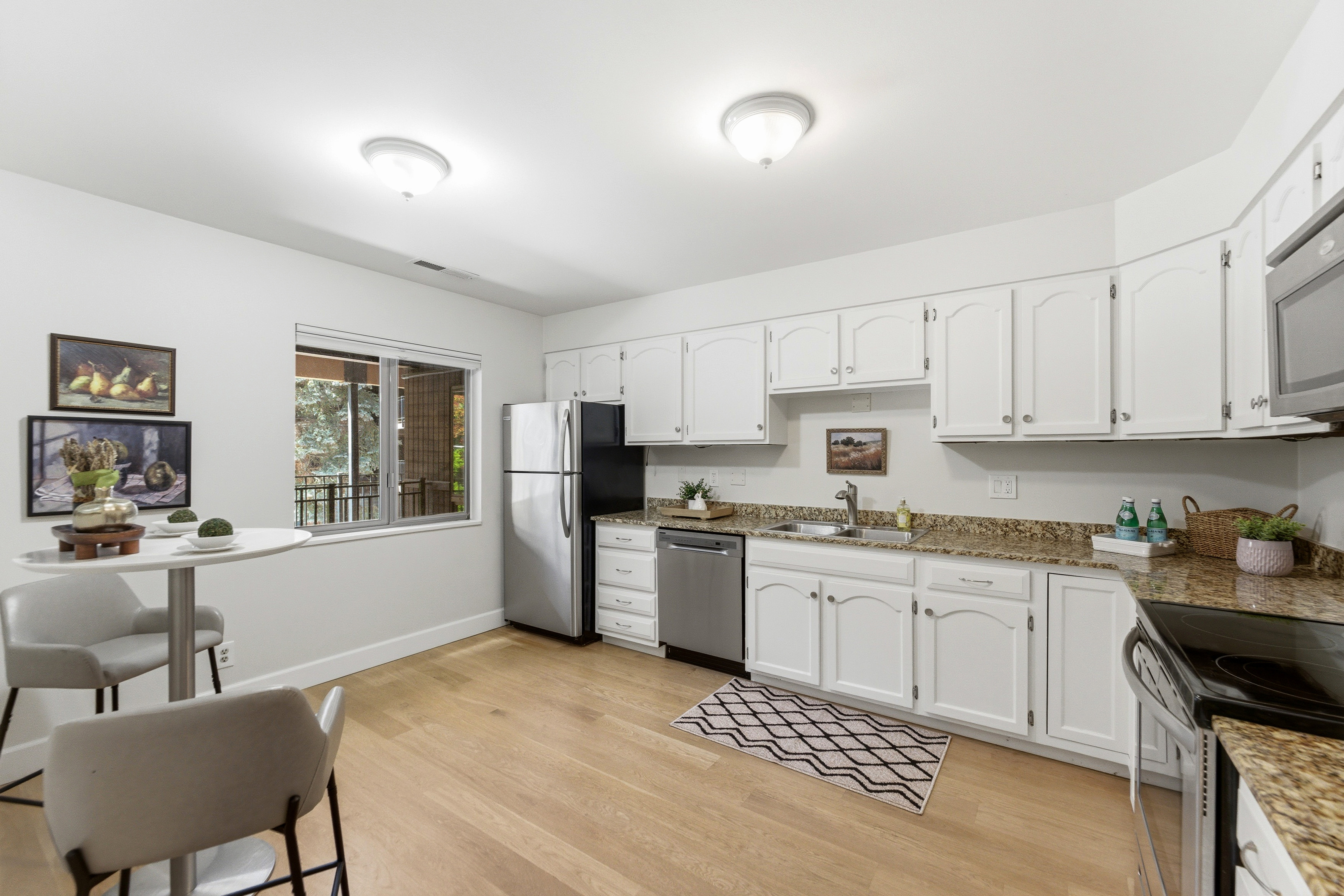 Kitchen featuring light wood-finish flooring, white cabinetry, and mottled stone countertops