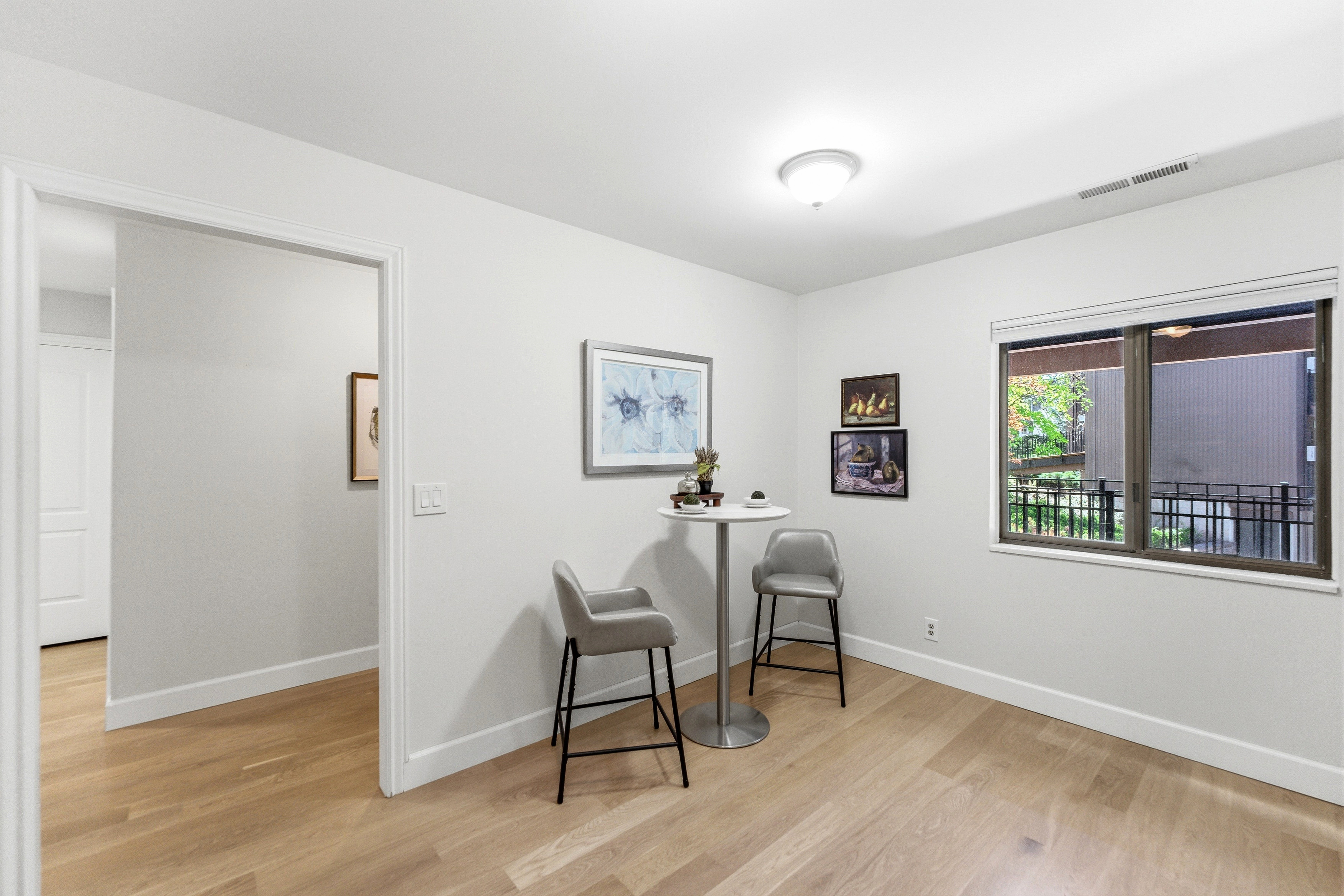 Bright room with wood-finish flooring, a contemporary ceiling light fixture, a window with a black frame, and a wide entryway