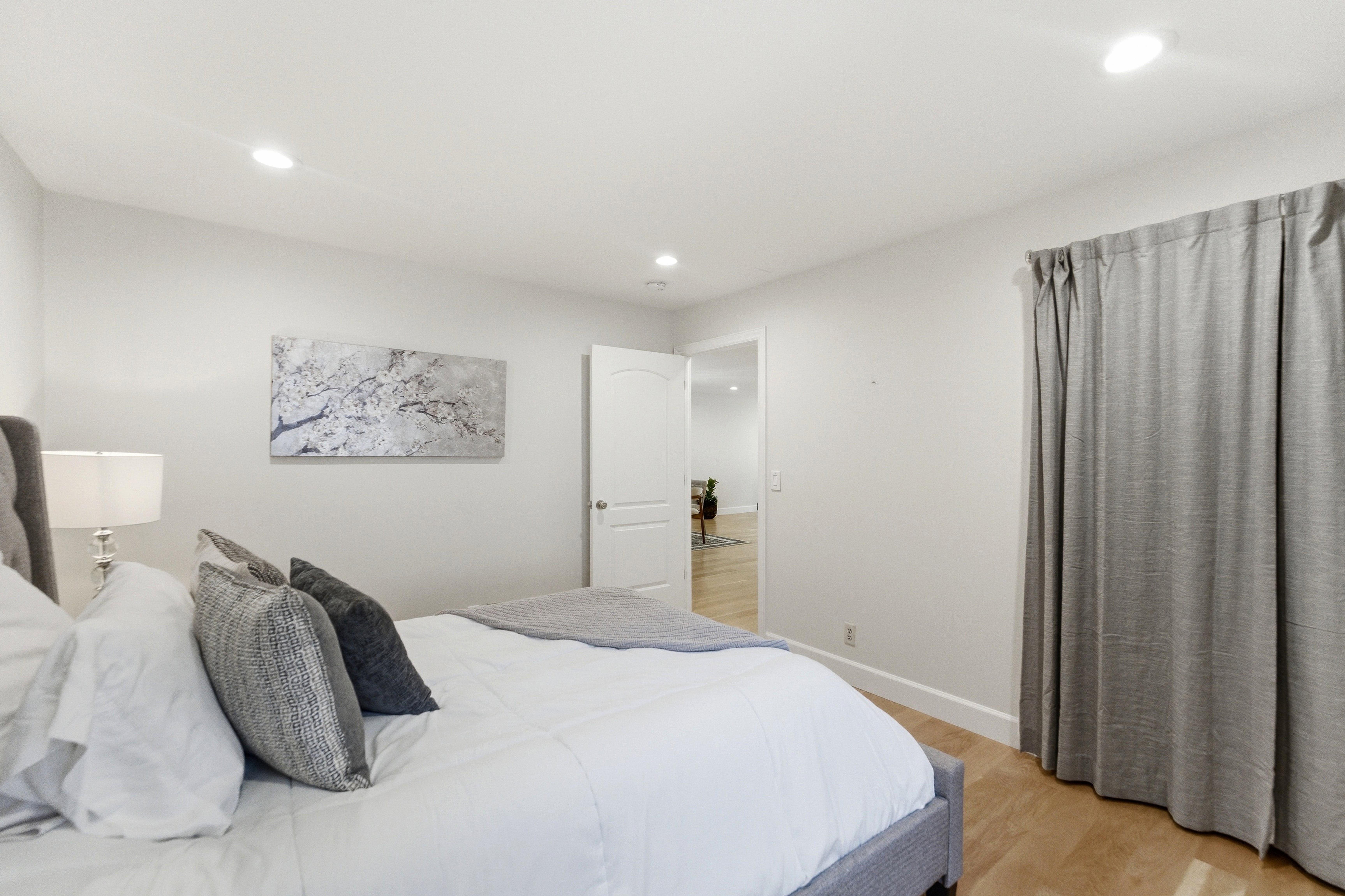 Light-toned wood-finish flooring complements the neutral wall color and recessed lighting