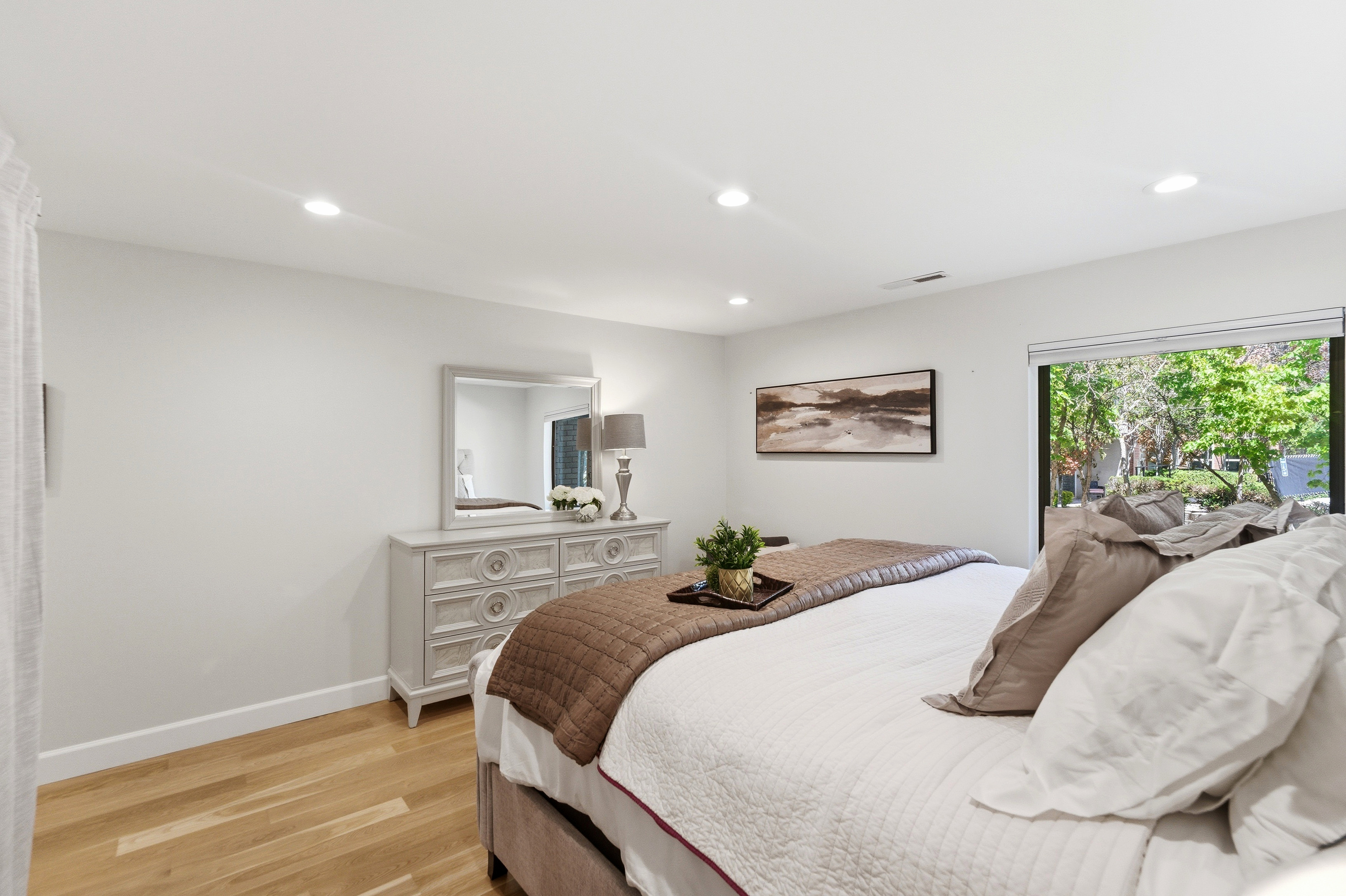 Spacious room featuring natural wood-finish flooring, recessed lighting, and a large sliding glass door providing abundant natural light