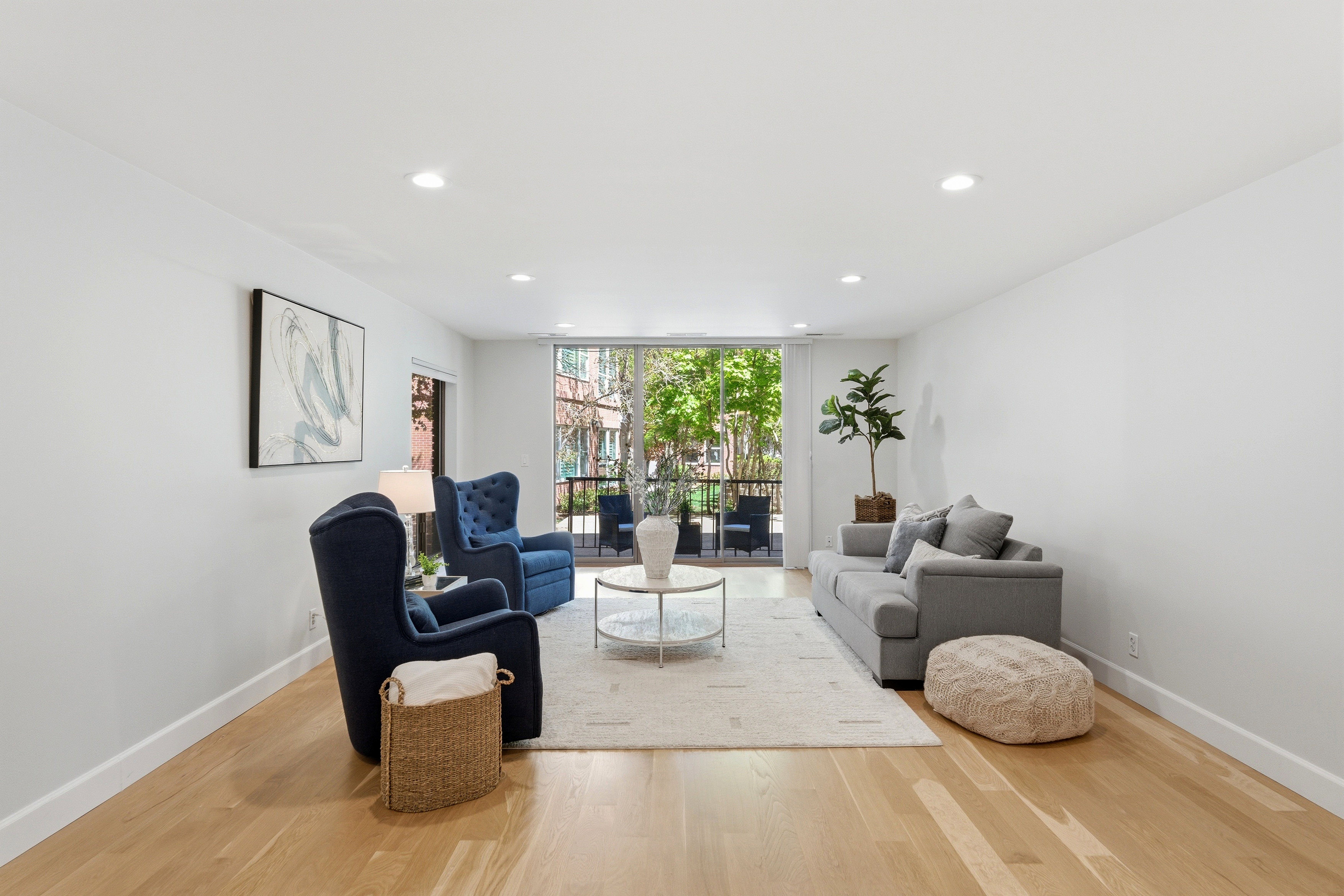 Spacious living area featuring light wood-finish flooring, recessed lighting, and a private balcony