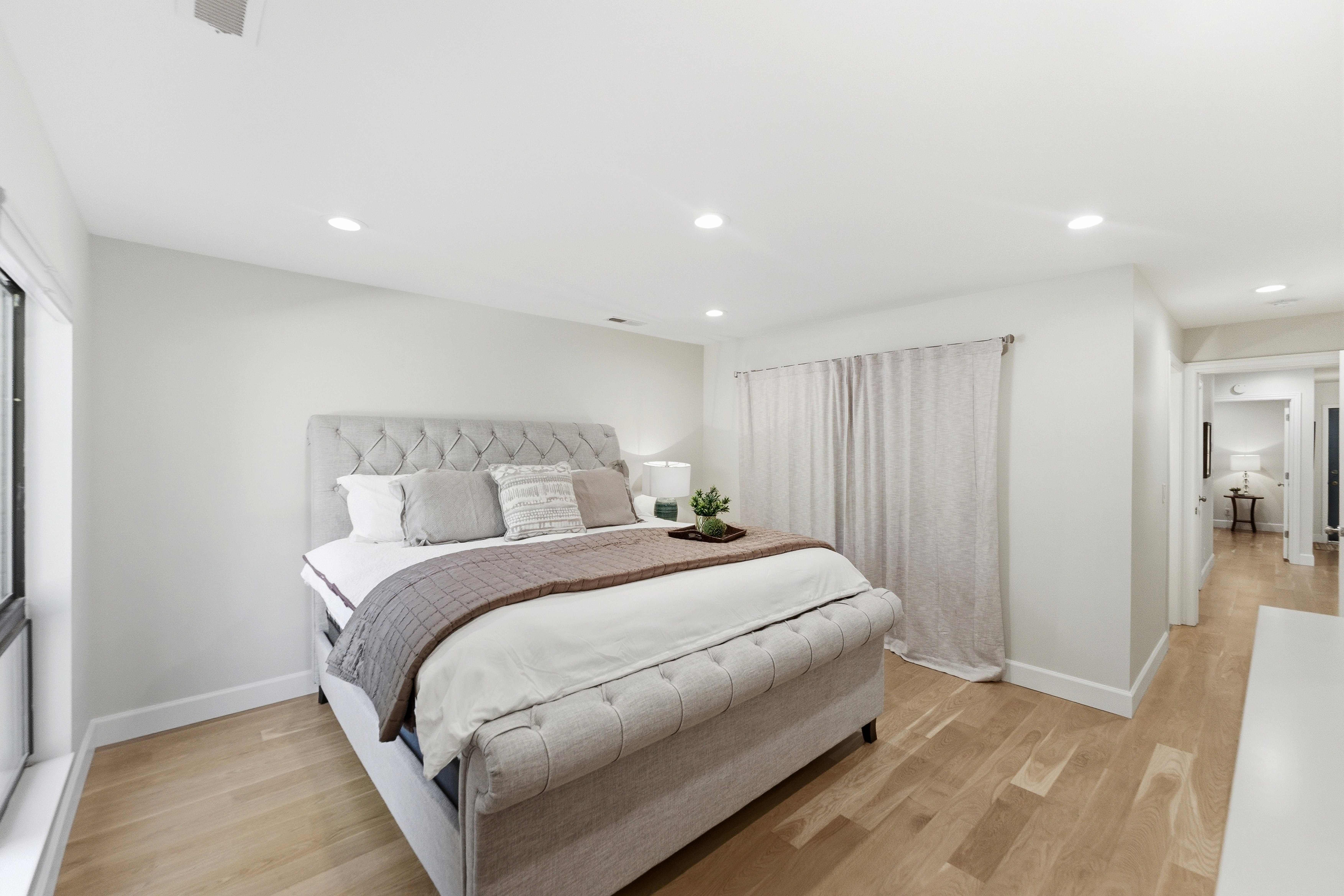 Spacious room featuring light wood-finish flooring, recessed lighting, expansive windows, and a wide entryway