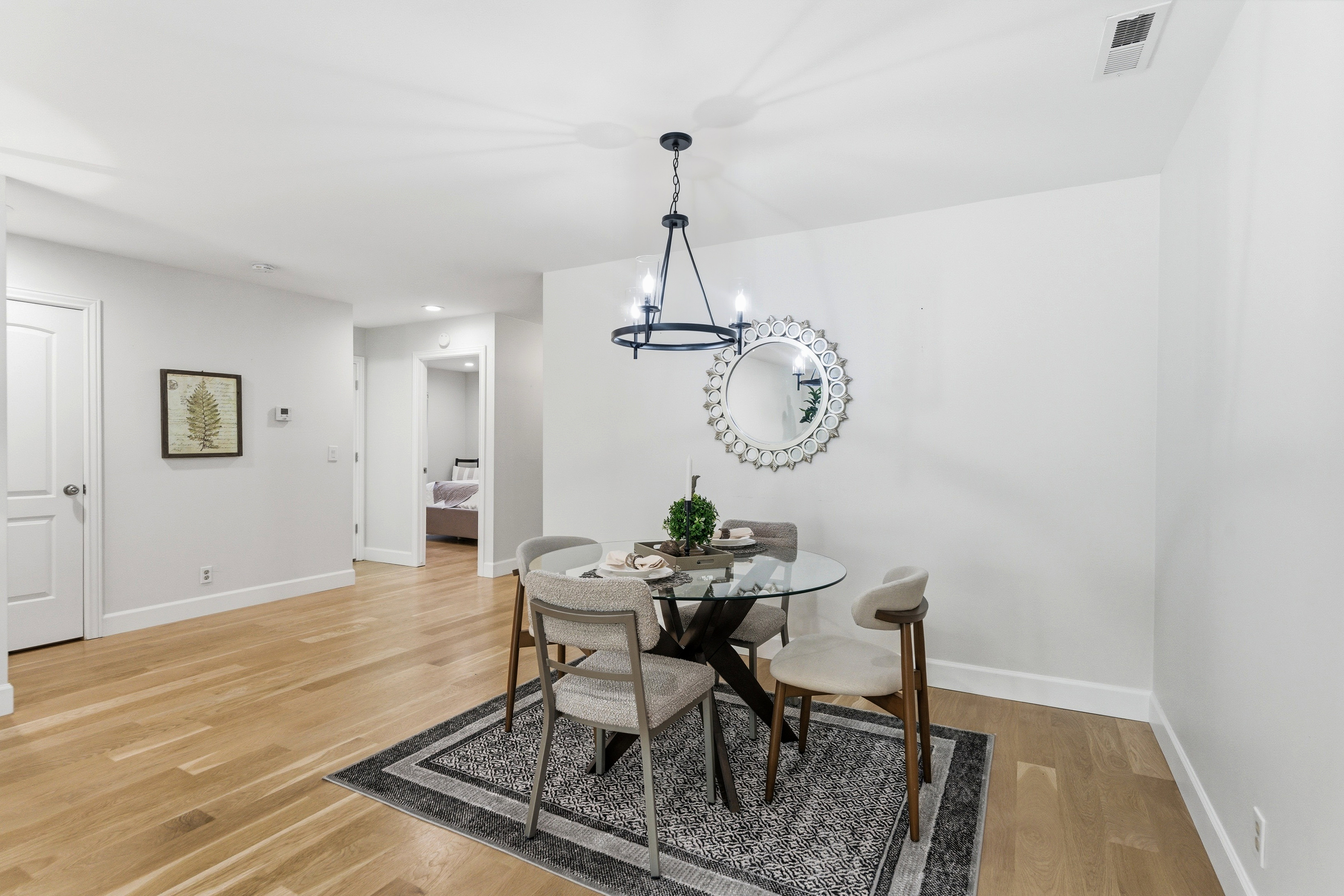 Dining area featuring wood-finish flooring, white walls, and a contemporary chandelier