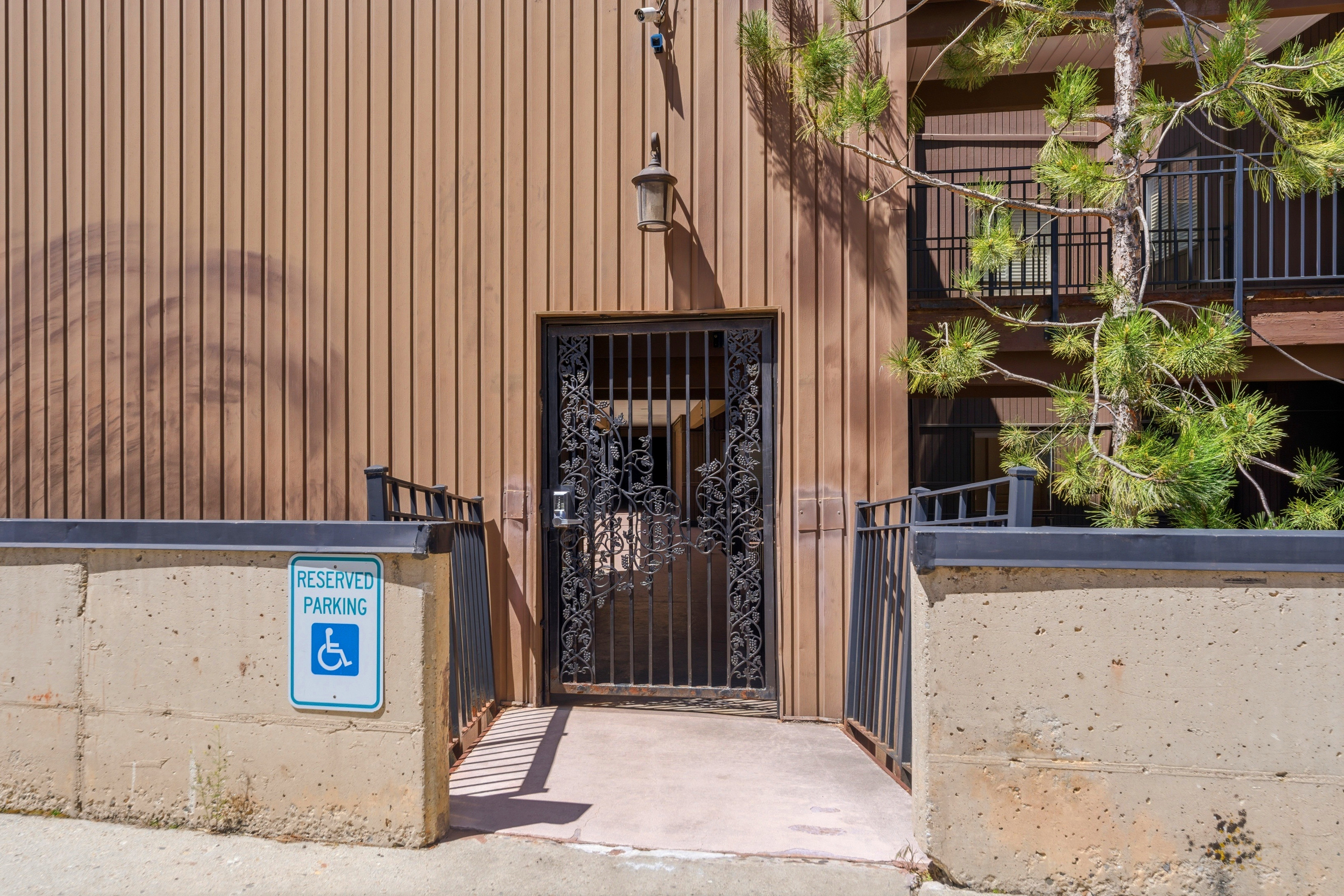Entrance with an ornate metal security door and exterior wall paneling