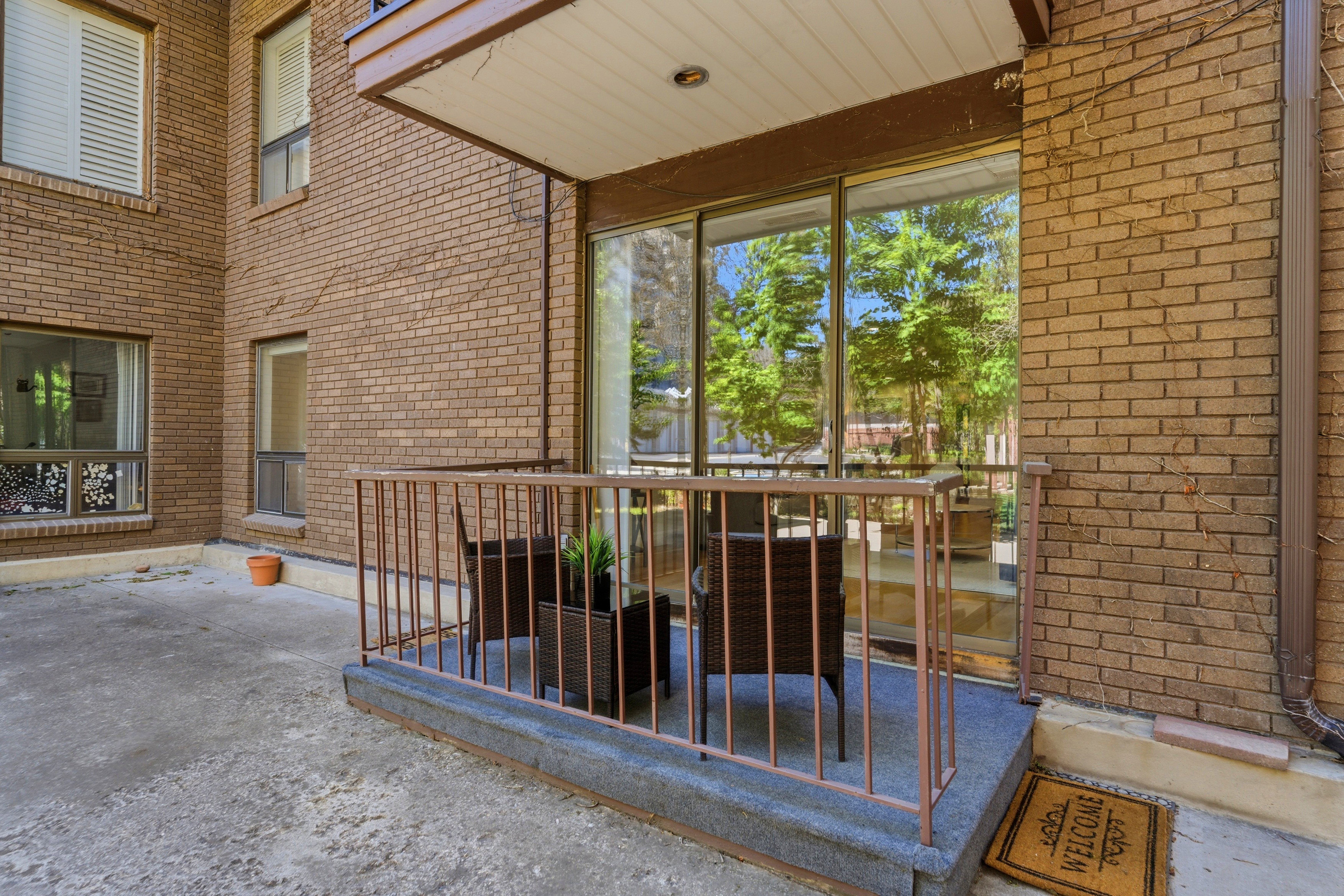 Patio area featuring a sliding glass door entry, brick facade, and a metal railing