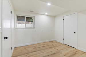 Interior room featuring wood-finish flooring, white walls, and recessed lighting
