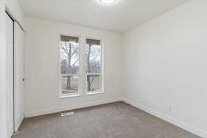 Neutral-toned carpeted interior space featuring white walls and trim