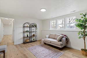 Bright, open room featuring wood-finish flooring, white walls, and three windows providing natural light