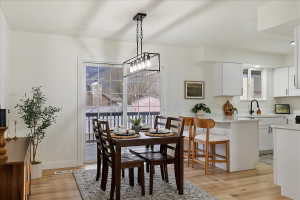 Open-concept dining area featuring wood-finish flooring, a contemporary chandelier, and direct outdoor access via sliding glass doors