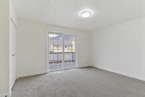 Spacious room featuring neutral carpet flooring, white walls, and a contemporary ceiling light fixture