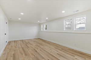 Spacious room featuring wood-finish flooring, white walls, and recessed lighting