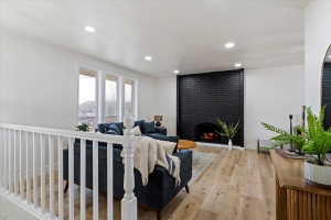 Spacious living area featuring a black brick fireplace, wood-finish flooring, recessed lighting, and multiple large windows