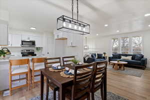 Open-concept living space featuring wood-finish flooring, recessed lighting, and a modern rectangular chandelier