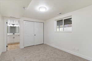 Carpeted interior room with white walls, a single window, and a double sliding closet door