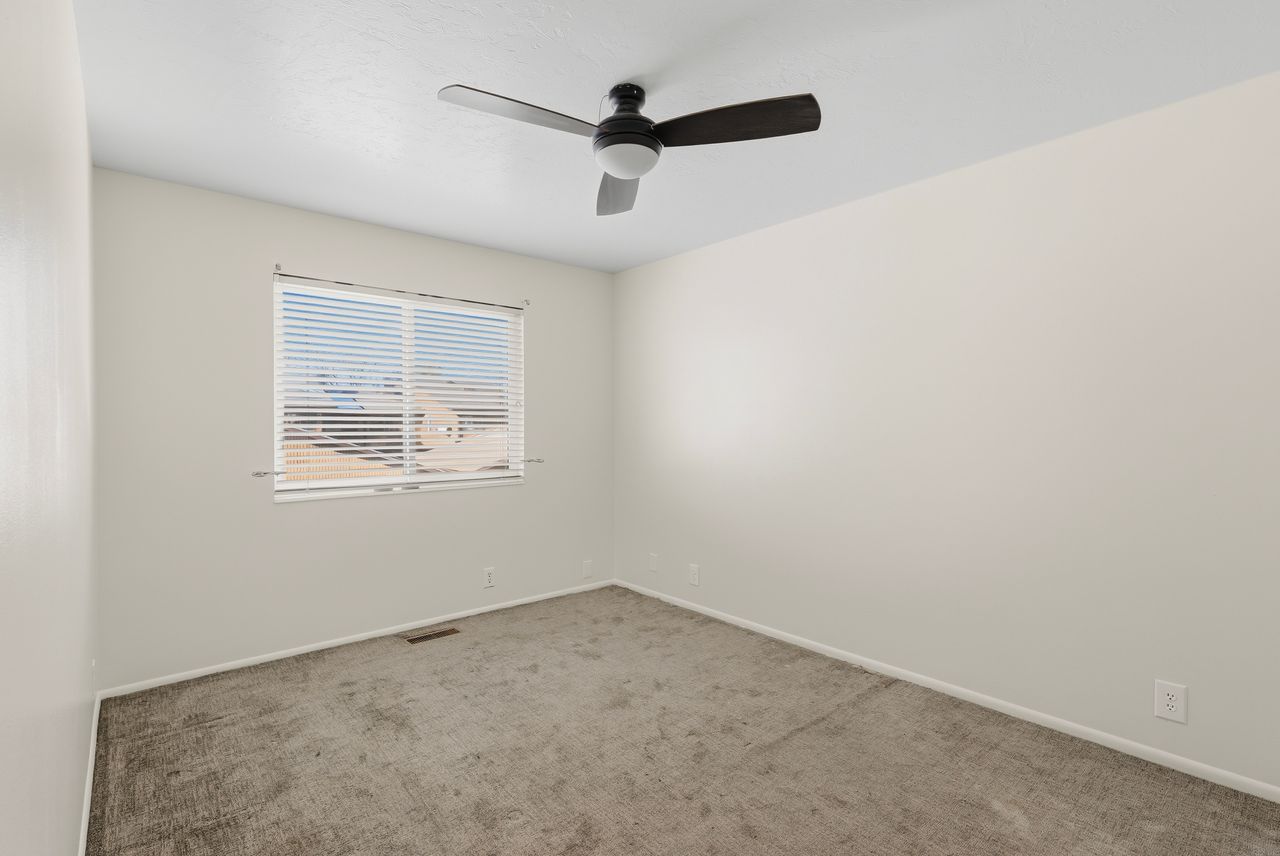 Carpeted empty room with baseboards and a ceiling fan