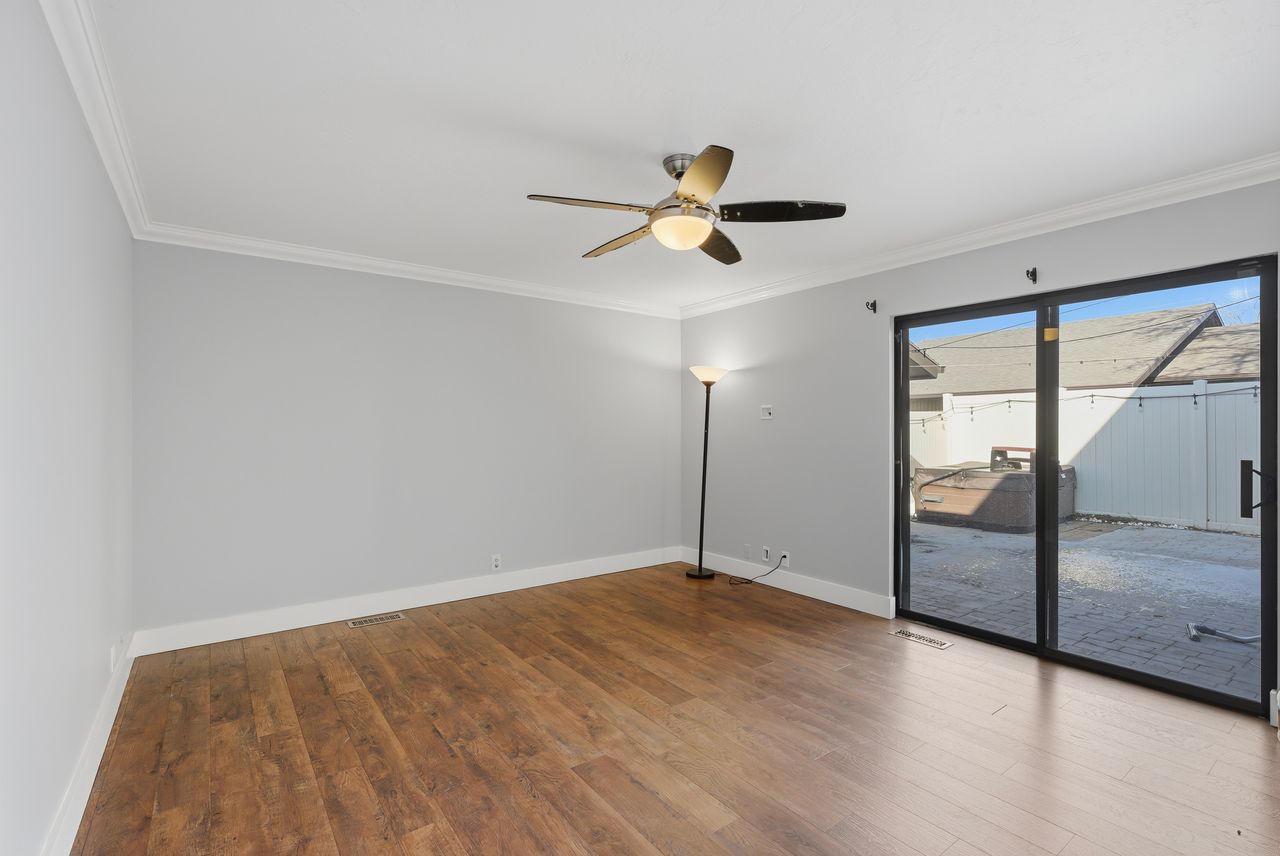 Unfurnished room featuring dark wood-style flooring, ornamental molding, and a ceiling fan