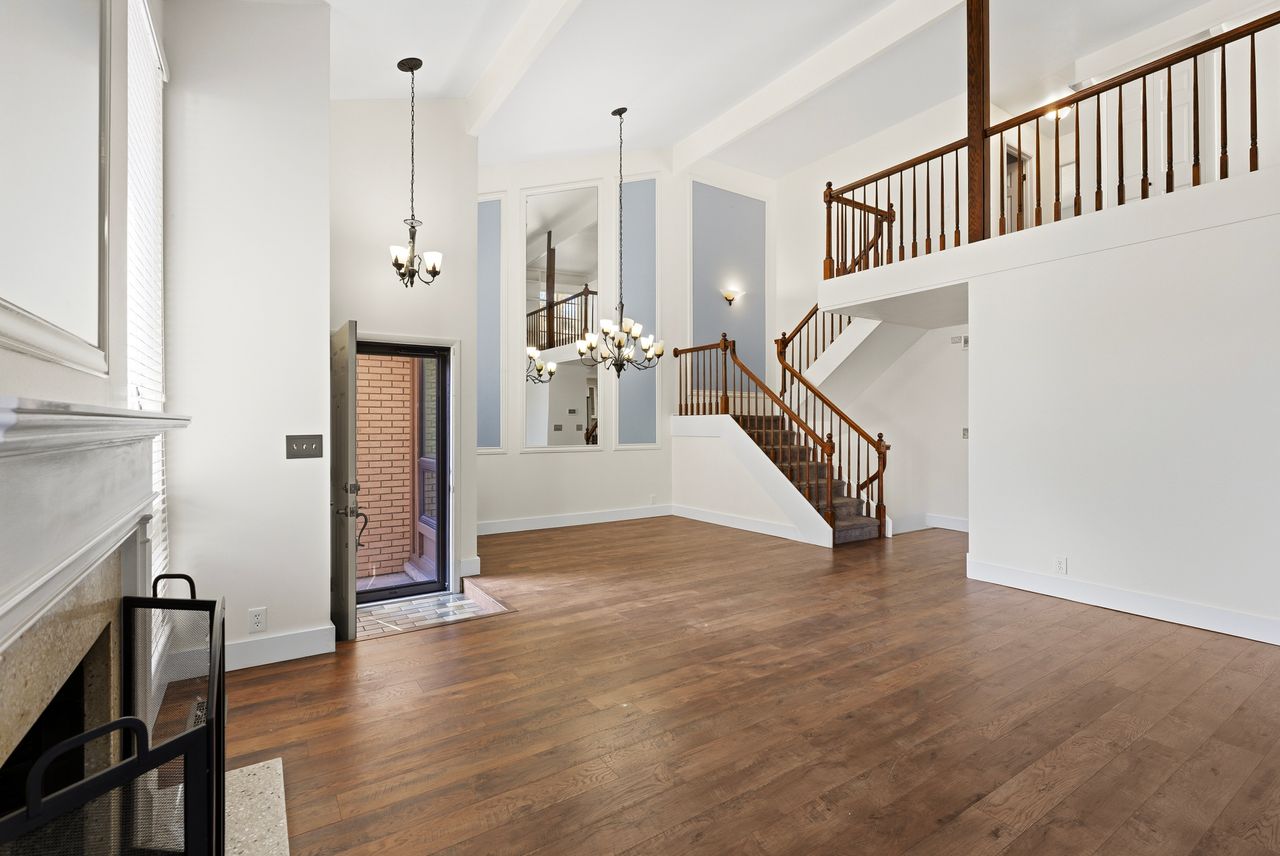 Unfurnished living room featuring dark wood-type flooring, hanging lights, and lofted ceiling
