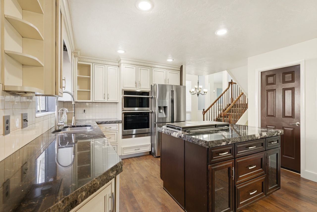 Kitchen with dark stone counters, a center island, stainless steel appliances, open shelves, and two tone color scheme