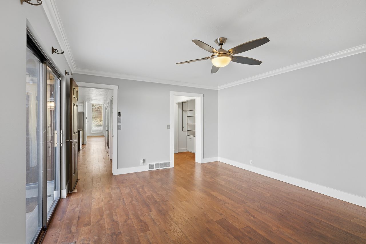 Unfurnished room with ornamental molding, dark wood-style flooring, and a ceiling fan