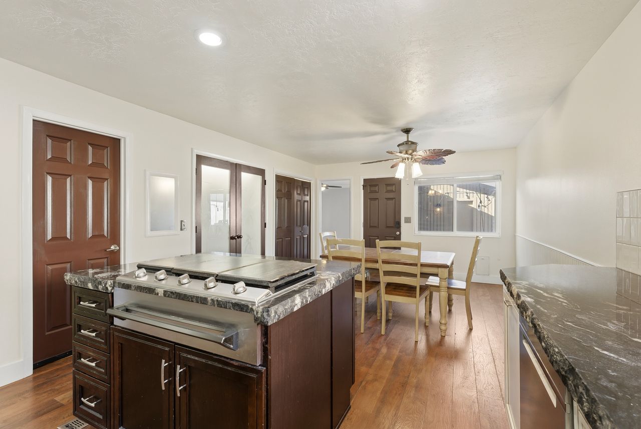 Kitchen featuring dark wood finish cabinetry, dark wood-type flooring, ceiling fan, a center island, and dishwasher