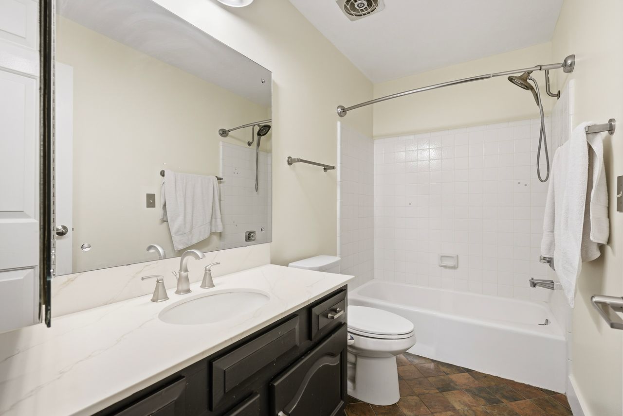 Bathroom featuring vanity, bathing tub / shower combination, and stone finish flooring