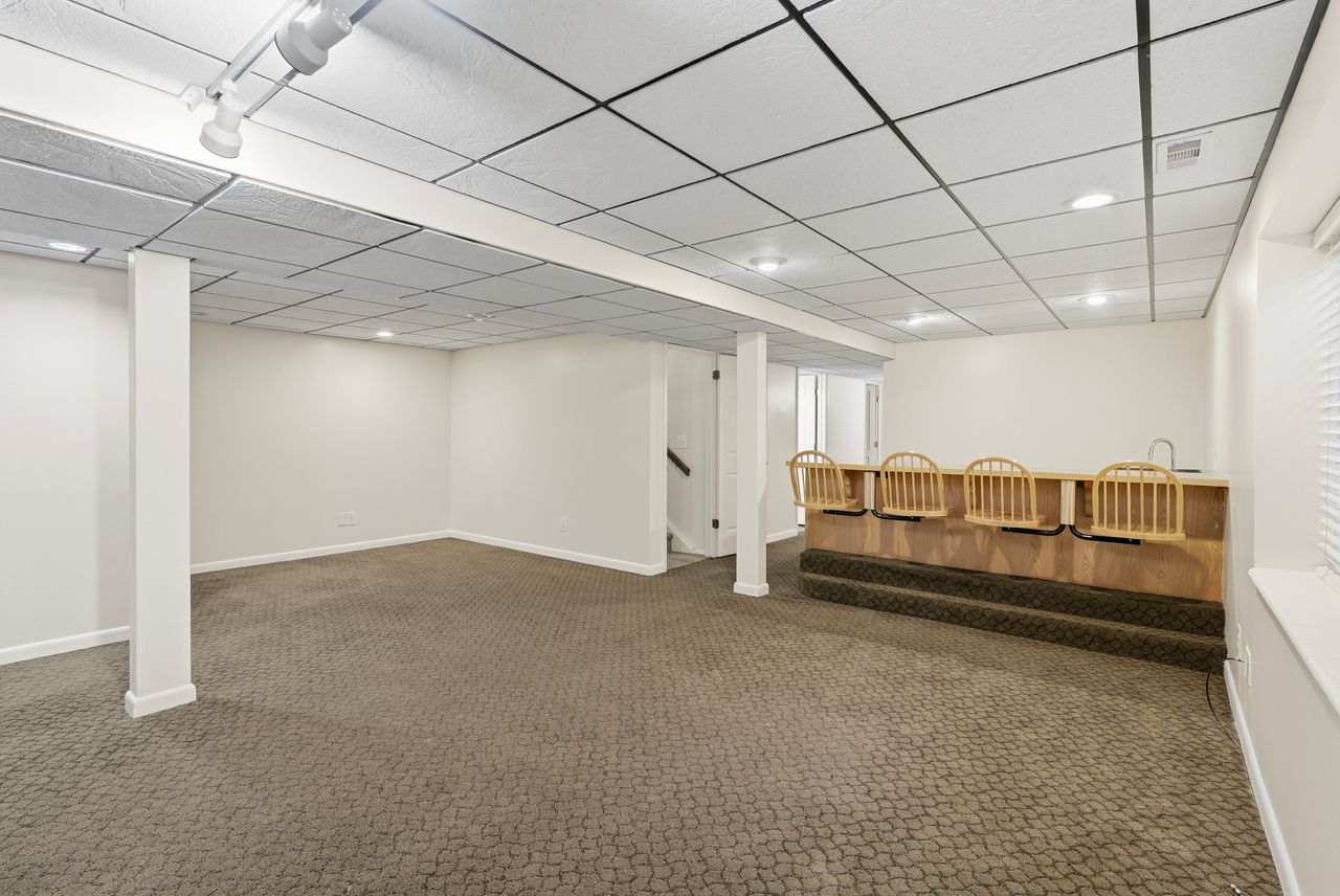 Finished basement featuring a paneled ceiling and dark carpet