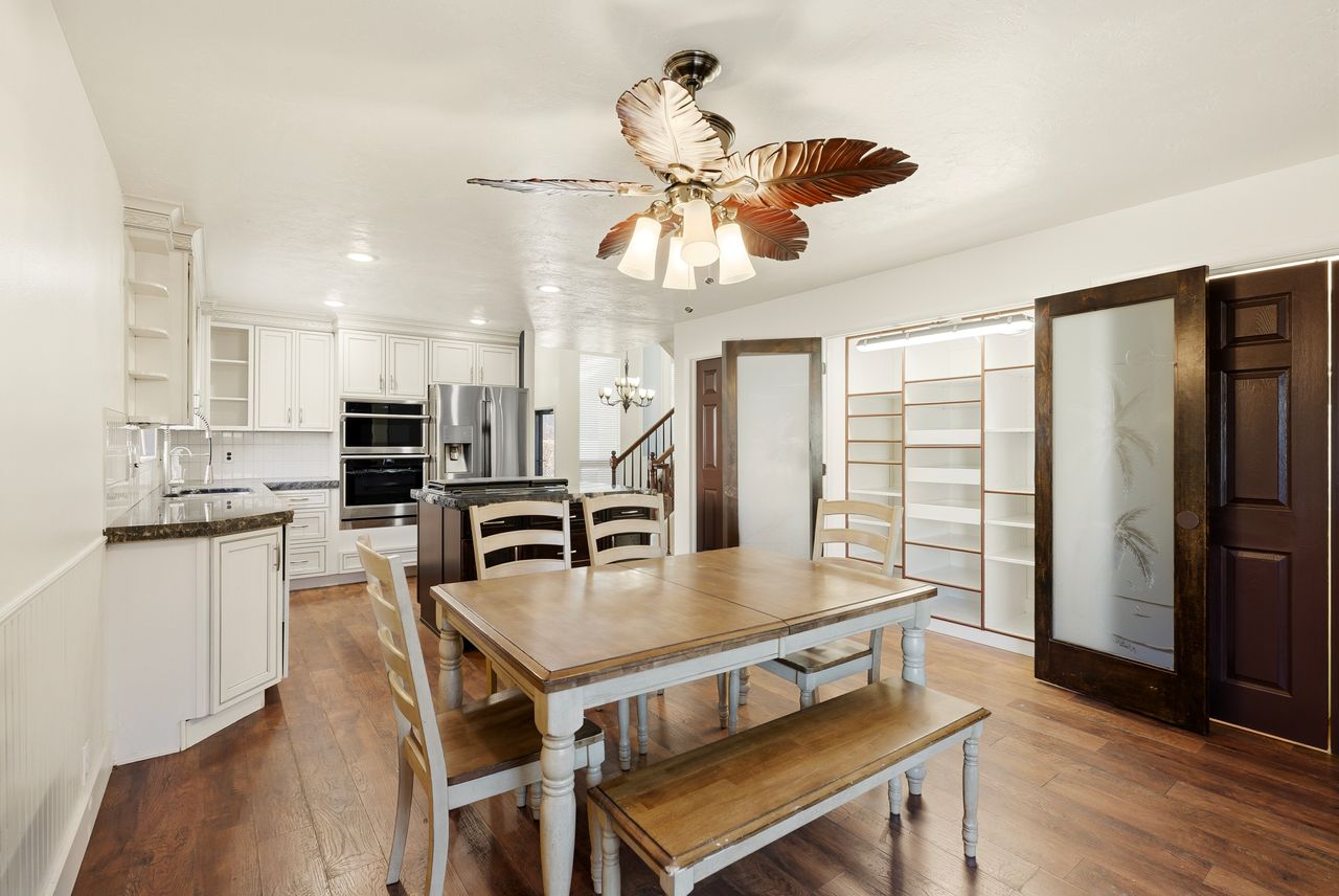 Dining area with dark wood-style floors, a ceiling fan, and a chandelier