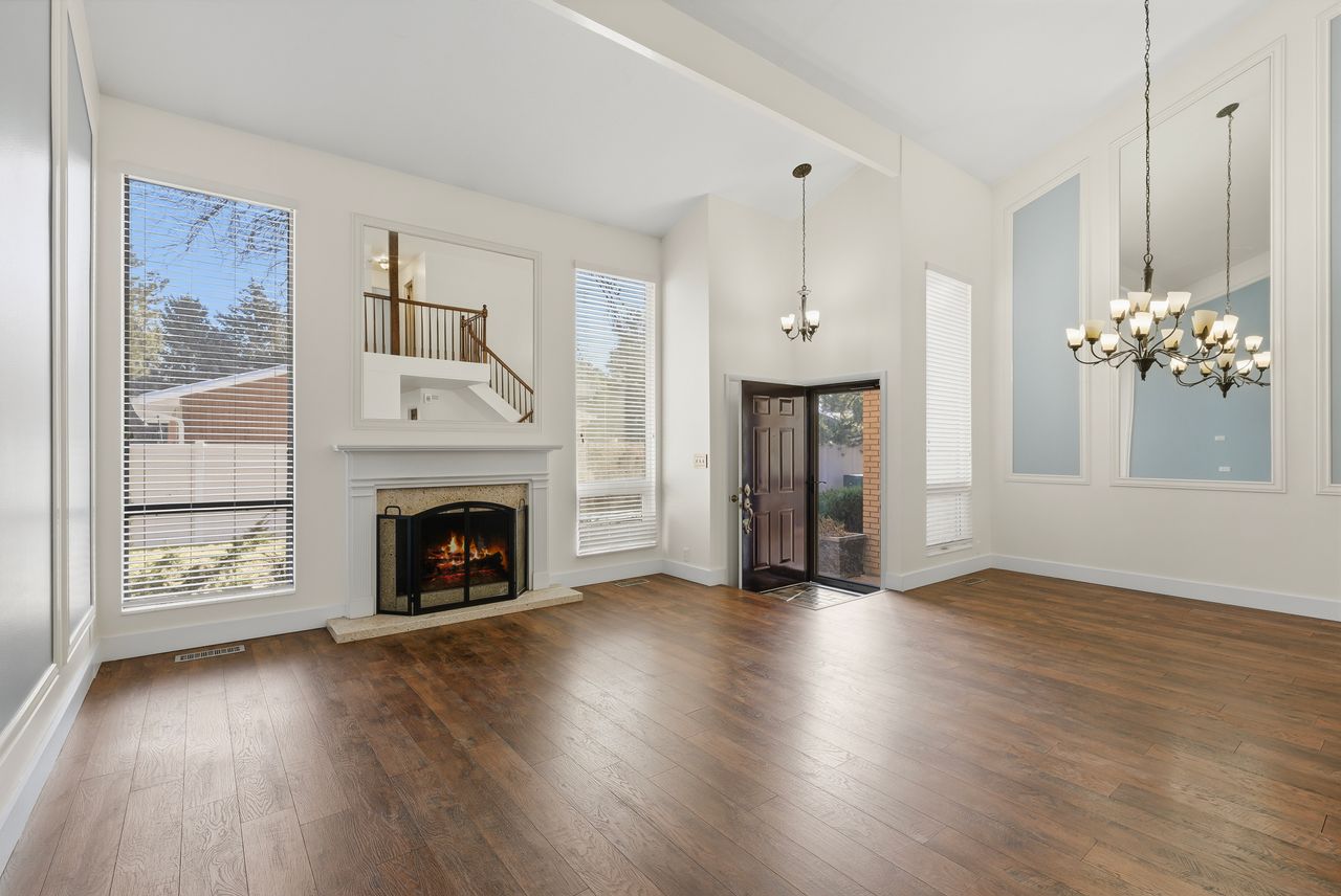 Unfurnished living room featuring dark wood-type flooring, suspended lighting, healthy amount of natural light, and a high ceiling