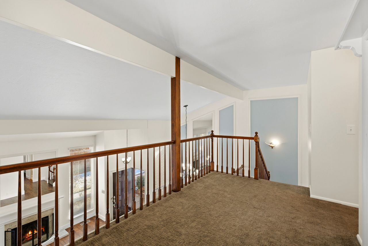 Hall with lofted ceiling with beams, carpet, and an upstairs landing