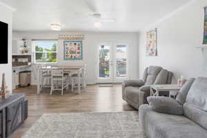 Open-concept living area featuring wood-finish flooring, white walls, and crown molding