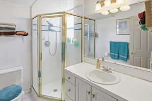 Bathroom featuring a corner shower with a gold-toned frame, an integrated vanity sink, a broad wall-mounted mirror, and a multi-light fixture