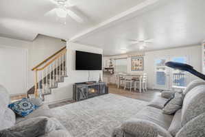 Open-concept living area with wood-finish flooring, a contemporary electric fireplace console, and multiple ceiling fans