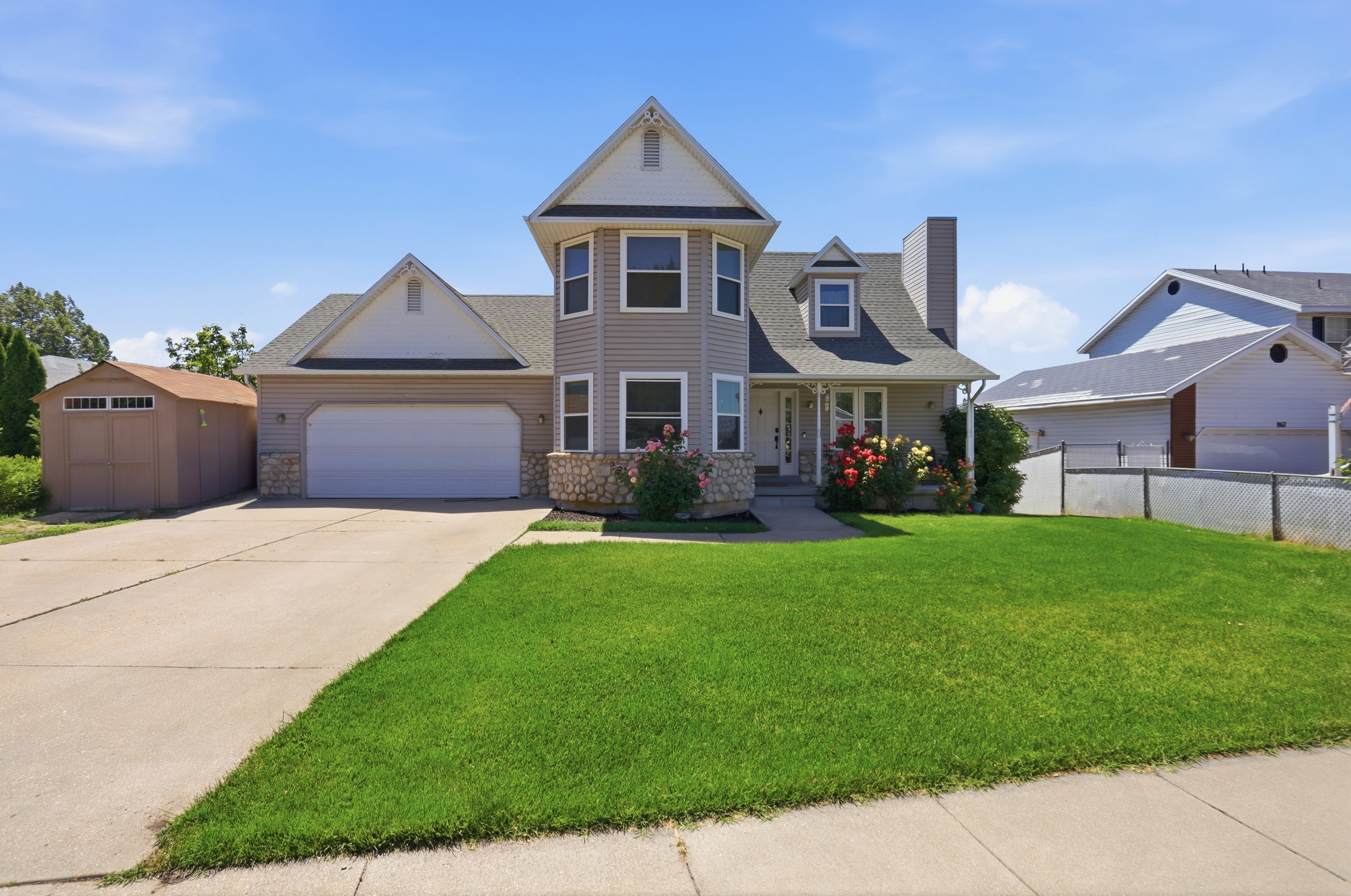 Multilevel residence featuring a two-car garage, dormer windows, and a stone facade