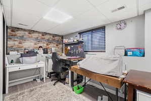 Finished room featuring a wood-look accent wall and suspended ceiling with recessed lighting