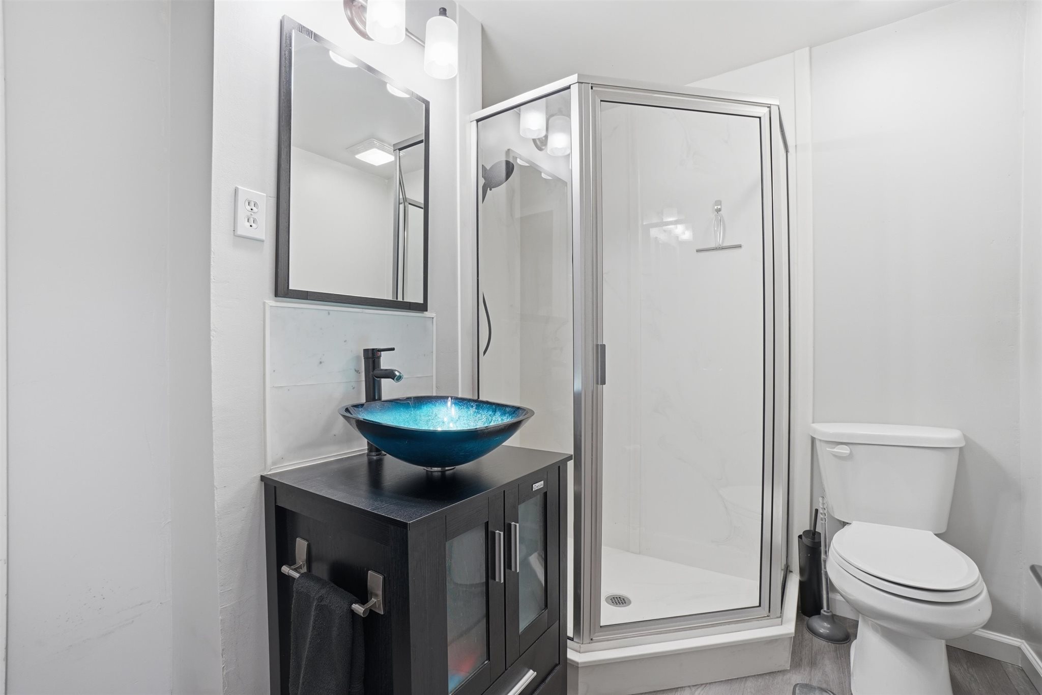 Bathroom featuring a glass vessel sink, dark wood-finish vanity, matte black faucet, and a stand-up shower with a glass enclosure