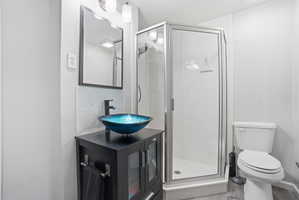 Bathroom featuring a glass vessel sink, dark wood-finish vanity, matte black faucet, and a stand-up shower with a glass enclosure