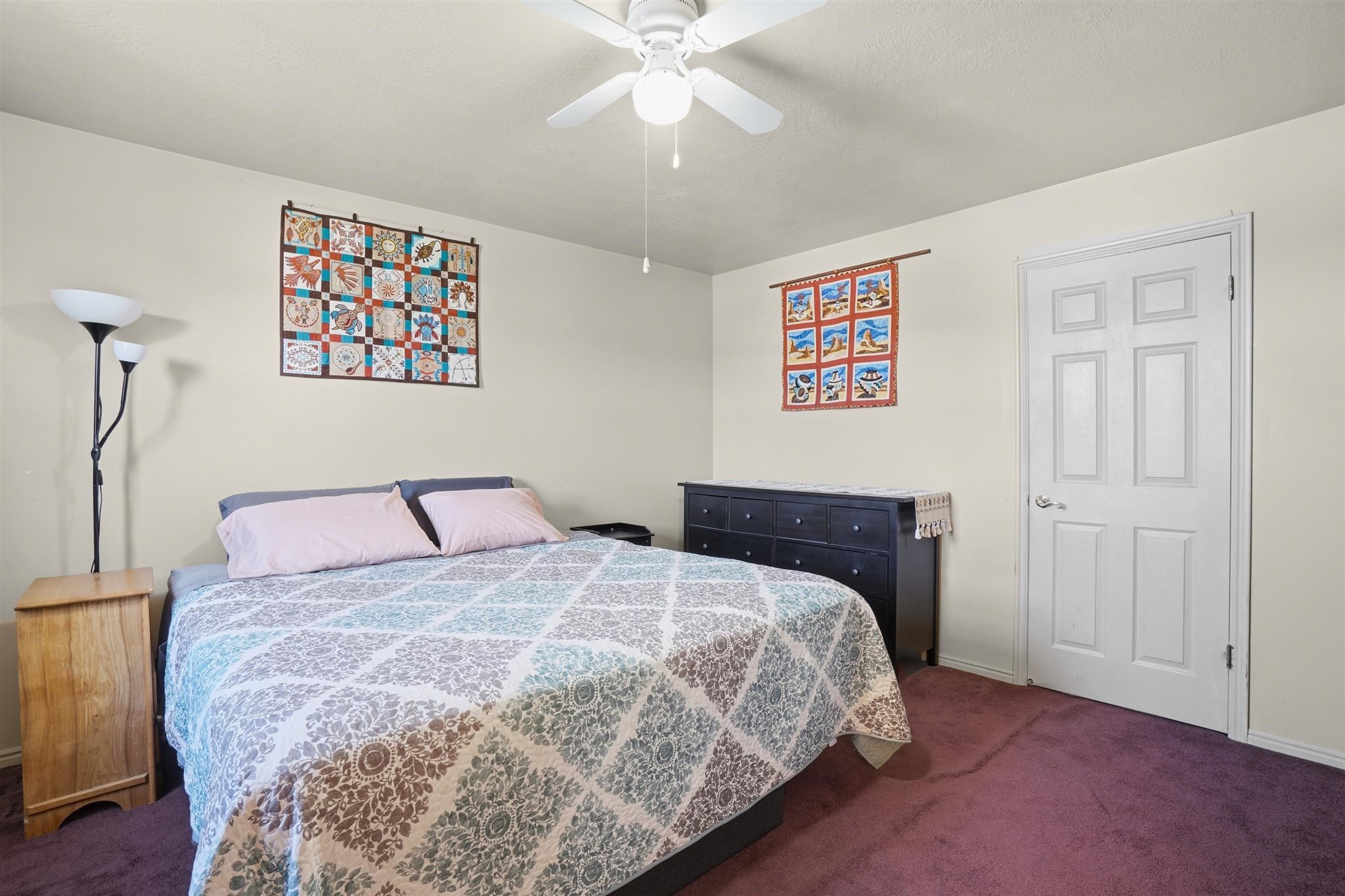 Bedroom featuring a ceiling fan with integrated lighting, neutral wall paint, and purple carpet flooring