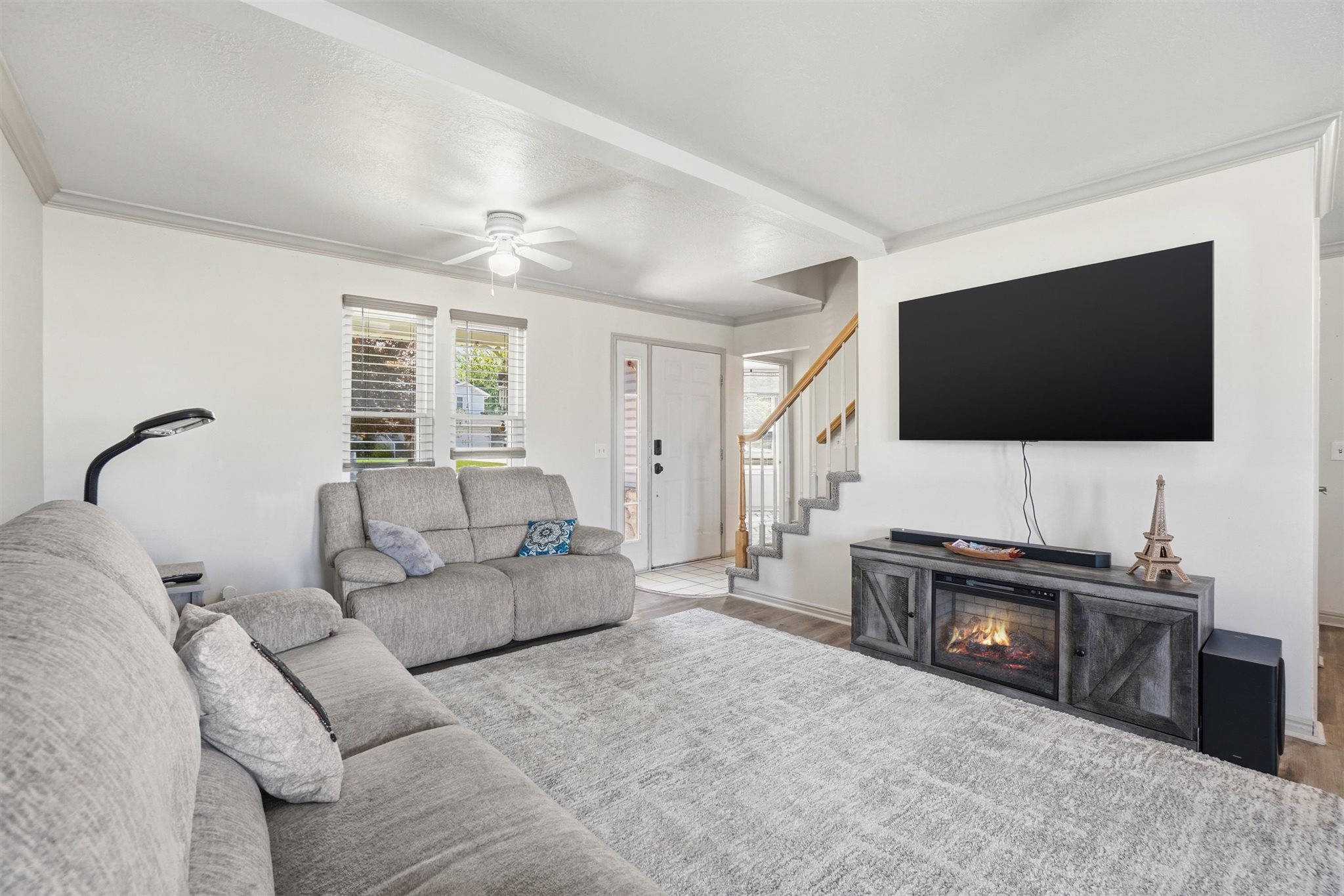 Spacious living area featuring light-toned walls and wood-finish flooring