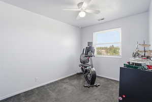 Bright room featuring a window with blinds, ceiling fan with light, gray wall-to-wall carpeting, and white baseboards