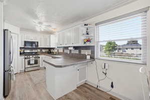 Bright kitchen featuring white cabinetry, stainless steel appliances, and wood-finish flooring