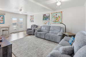 Spacious living area featuring wood-finish flooring, two ceiling fans with integrated lighting, and crown molding