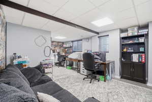 Spacious room featuring a drop ceiling with recessed lighting, exposed ceiling beams, and light gray wall paint